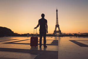 Homme arrivant en France devant tour eiffel avec valise